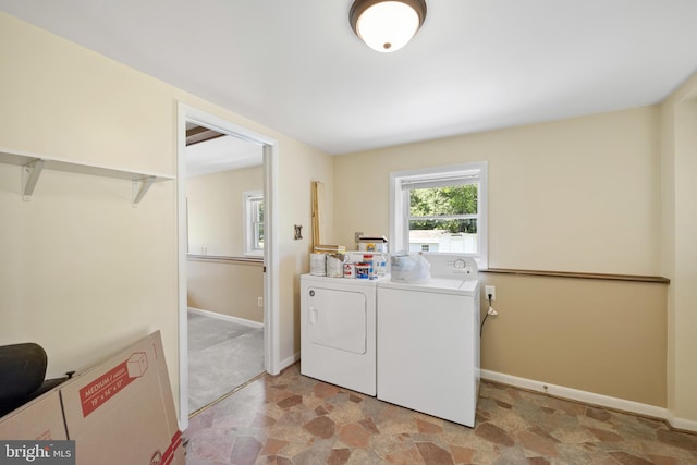 laundry room with laundry area, stone finish floor, baseboards, and separate washer and dryer