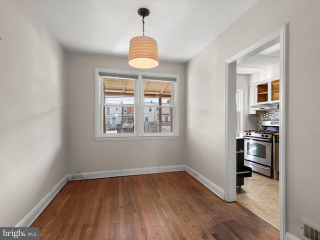 unfurnished dining area featuring visible vents, baseboards, and wood finished floors