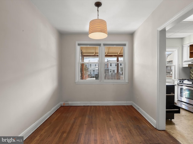 unfurnished dining area featuring wood-type flooring and baseboards