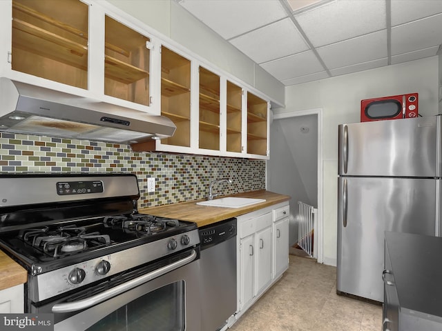 kitchen featuring appliances with stainless steel finishes, white cabinetry, a sink, wood counters, and under cabinet range hood