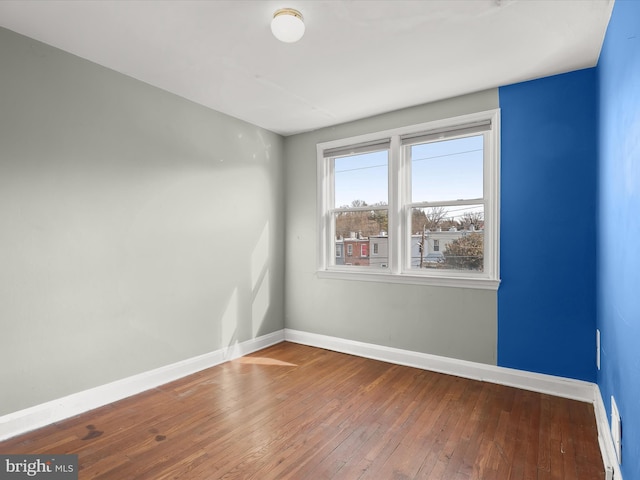 unfurnished room featuring hardwood / wood-style flooring and baseboards