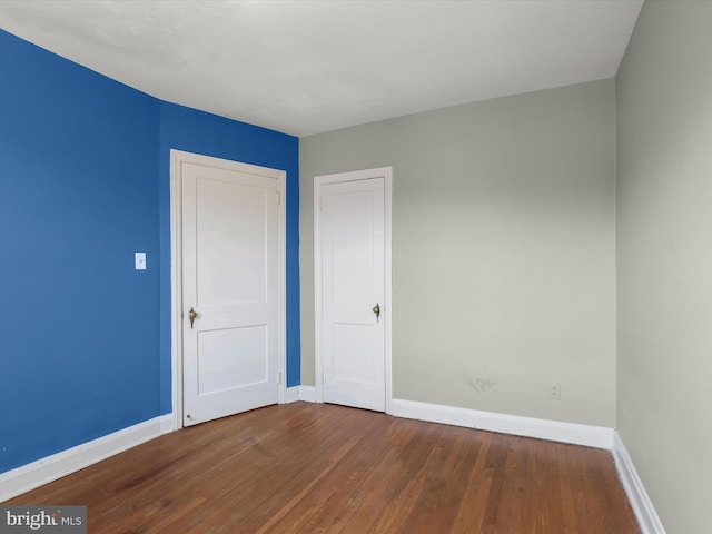 unfurnished bedroom with hardwood / wood-style flooring and baseboards