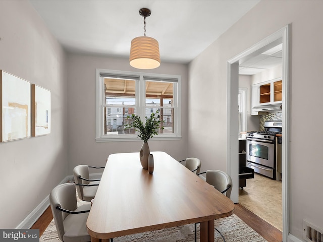 dining space featuring wood finished floors, visible vents, and baseboards