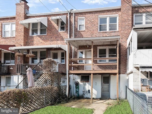 rear view of property with fence and brick siding