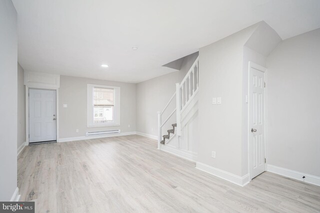 empty room featuring a baseboard radiator and light hardwood / wood-style floors