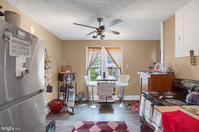 interior space with a textured ceiling, black / electric stove, stainless steel fridge, and wood-type flooring