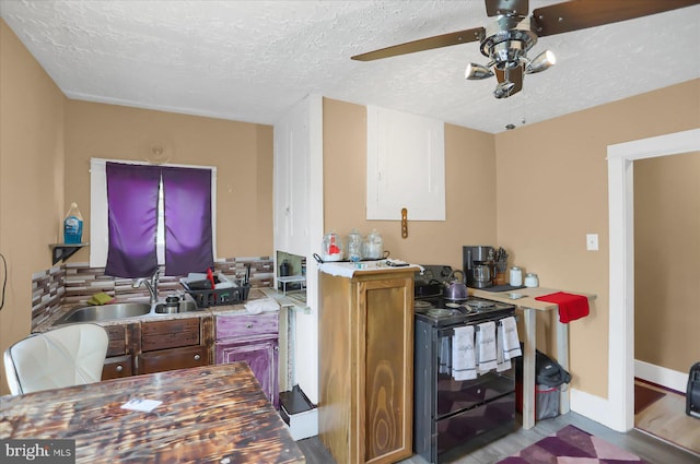 kitchen with light hardwood / wood-style floors, sink, black electric range, ceiling fan, and a textured ceiling