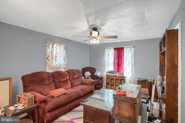 carpeted living room featuring ceiling fan and a textured ceiling