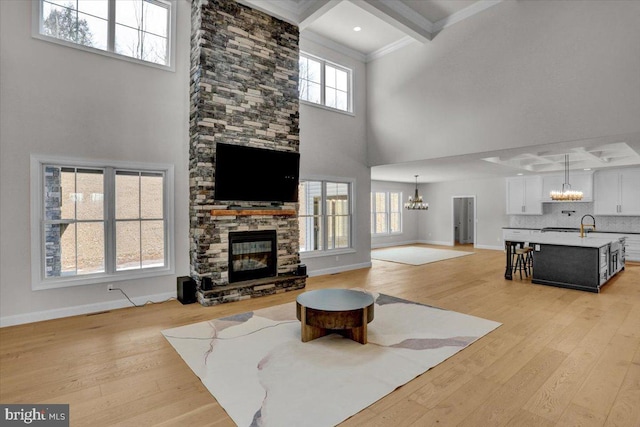 living area featuring baseboards, light wood-style floors, an inviting chandelier, and a fireplace