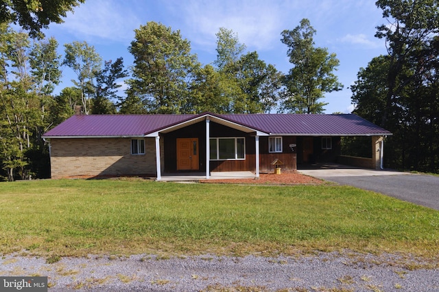 ranch-style house featuring metal roof, brick siding, driveway, a carport, and a front lawn