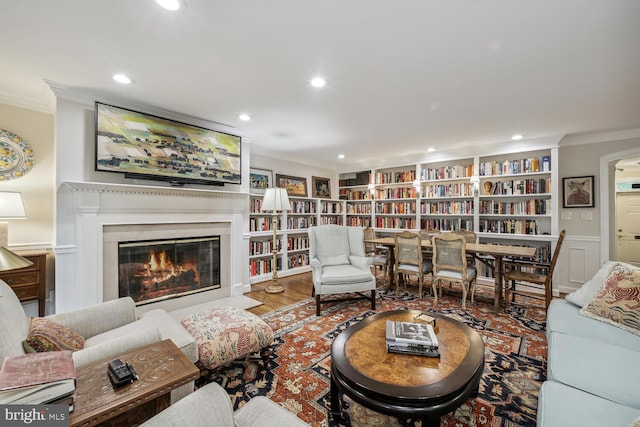 living room featuring built in features, ornamental molding, and wood-type flooring