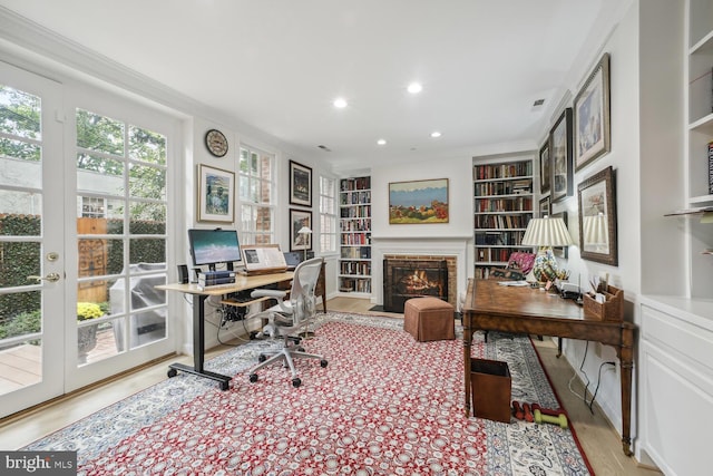 home office with built in shelves, french doors, light hardwood / wood-style flooring, and ornamental molding