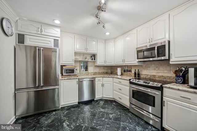 kitchen with backsplash, white cabinetry, light stone countertops, and stainless steel appliances