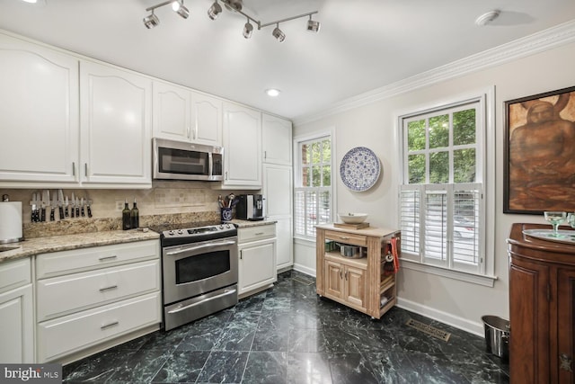 kitchen with decorative backsplash, white cabinets, appliances with stainless steel finishes, and crown molding