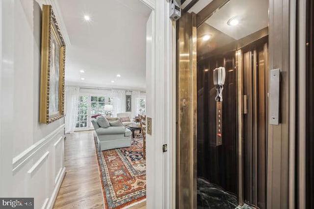 hallway with wood-type flooring and ornamental molding