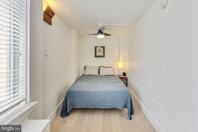 bedroom with light wood-type flooring, baseboards, and a ceiling fan