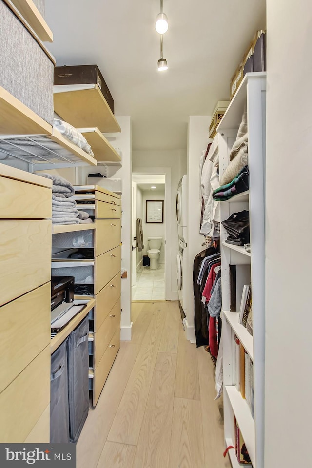 walk in closet with light wood-style floors and stacked washer / drying machine