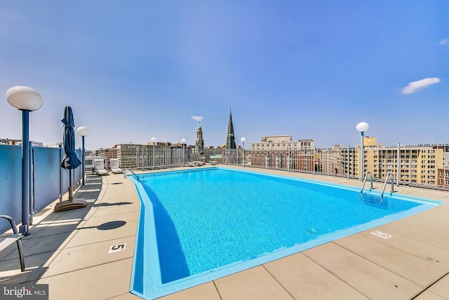 view of swimming pool featuring fence and a city view