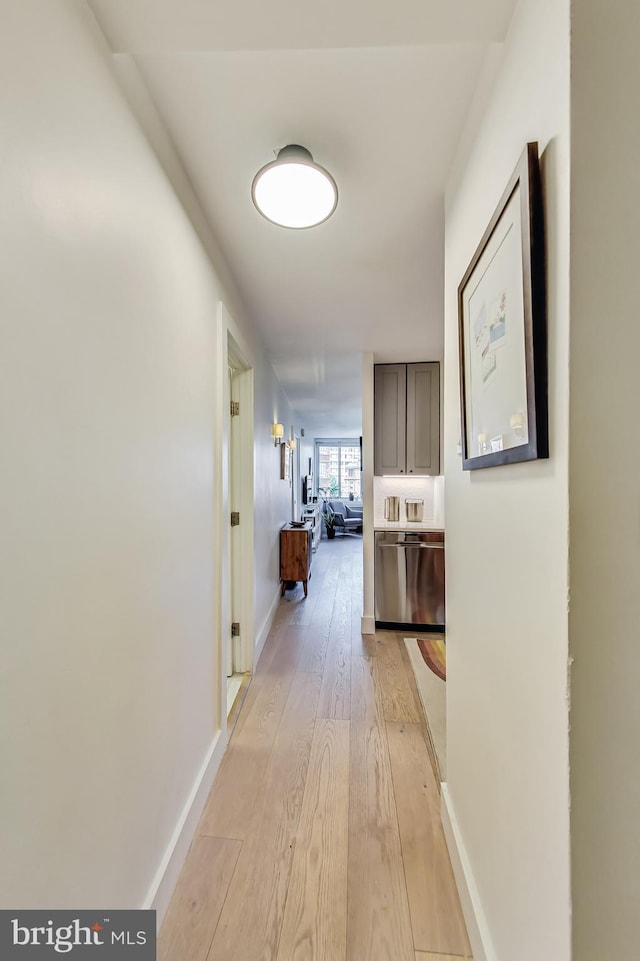 hallway featuring light wood-style flooring and baseboards