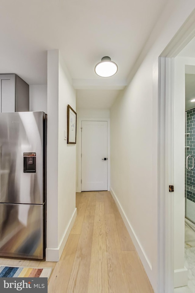 corridor featuring light wood-style flooring and baseboards