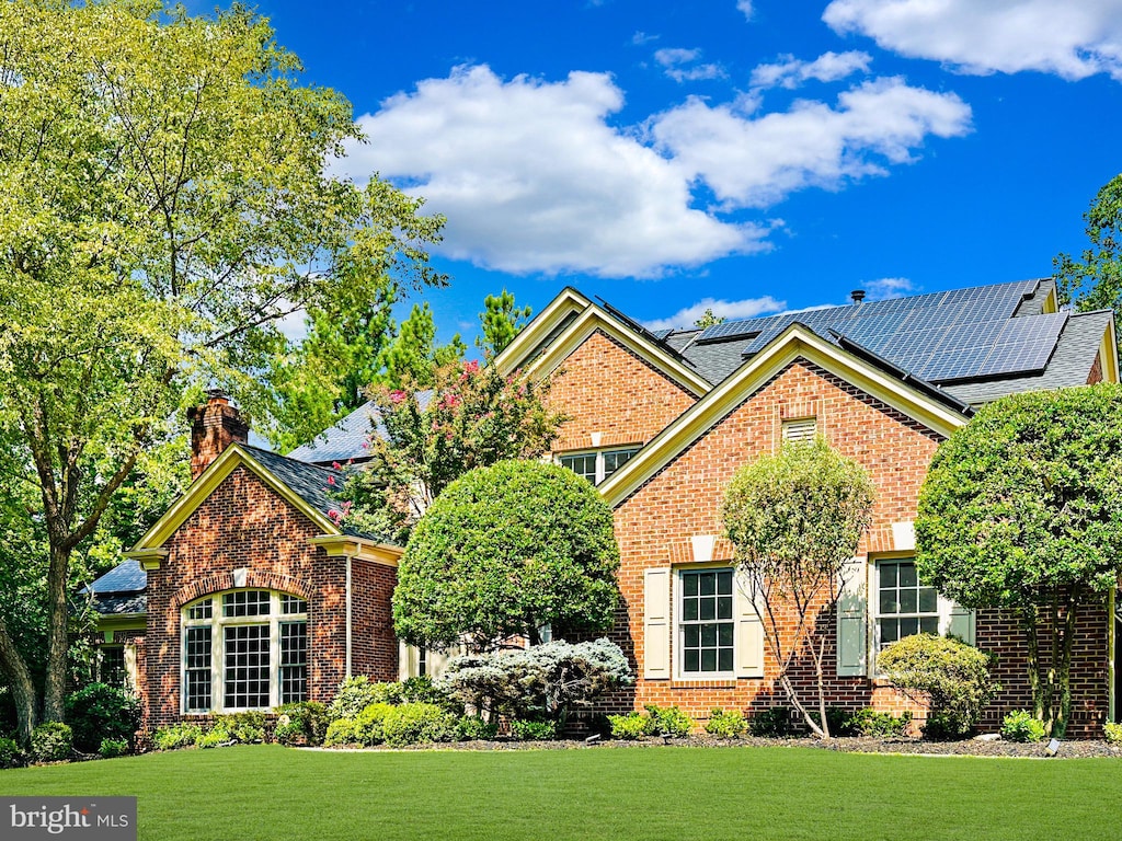 view of front of property featuring solar panels and a front lawn