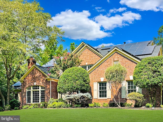 view of front of property featuring solar panels and a front lawn