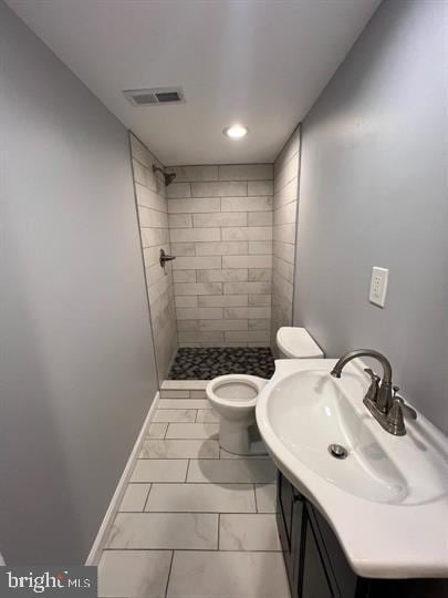 full bath featuring toilet, visible vents, vanity, baseboards, and a shower stall