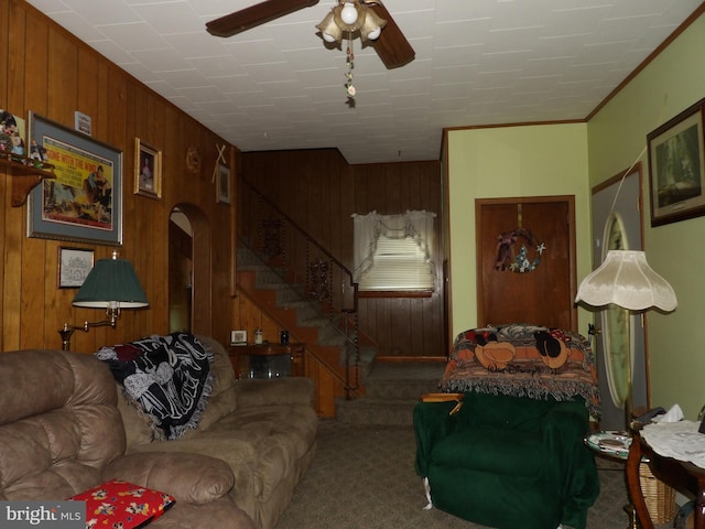 living room featuring wooden walls, ceiling fan, carpet floors, and crown molding