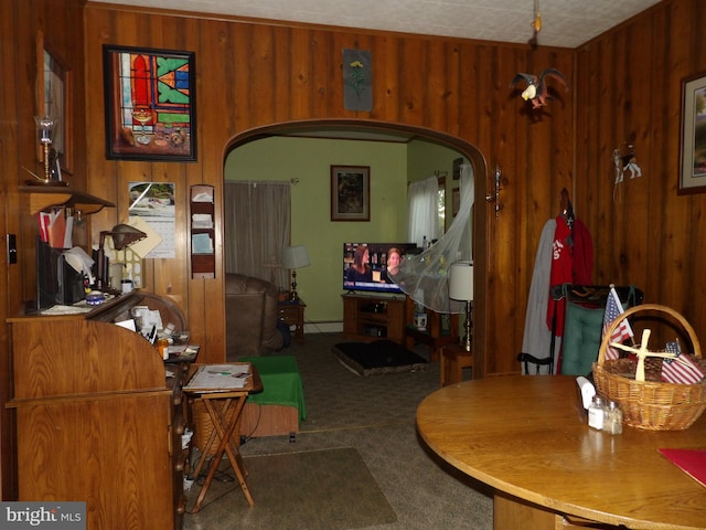 carpeted dining area featuring a textured ceiling and wood walls