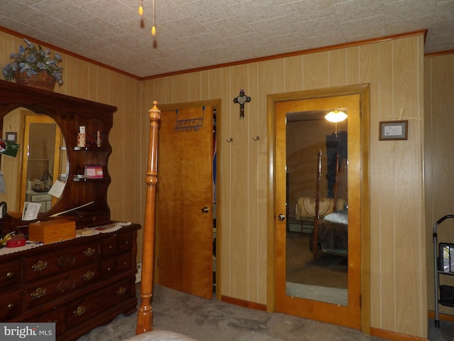 bedroom featuring carpet floors, wood walls, and ornamental molding