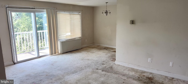 carpeted spare room featuring a chandelier