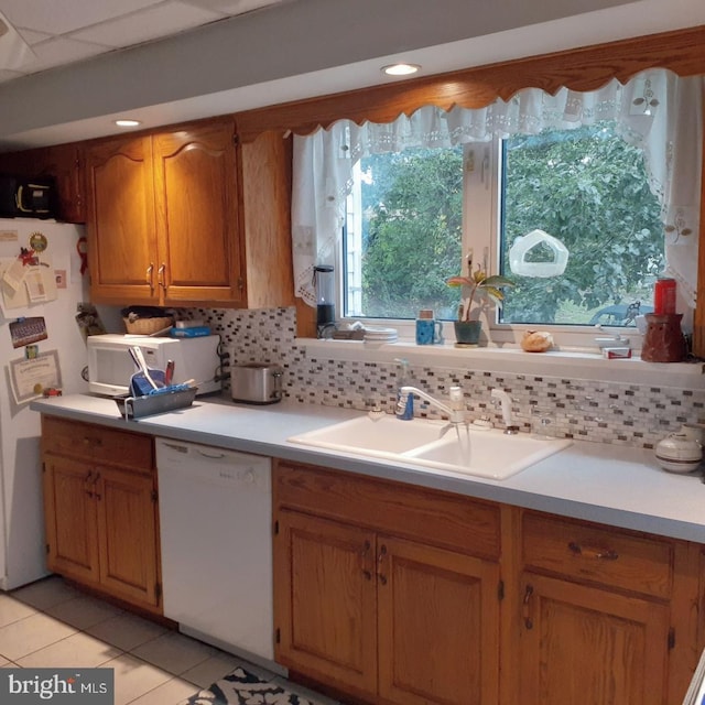 kitchen with white appliances, light tile patterned flooring, sink, and tasteful backsplash