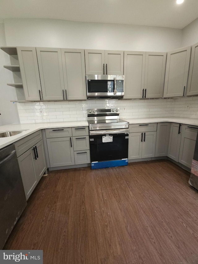 kitchen with stainless steel appliances, dark hardwood / wood-style floors, gray cabinets, and backsplash