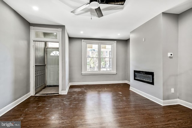 unfurnished living room featuring ceiling fan and dark hardwood / wood-style floors