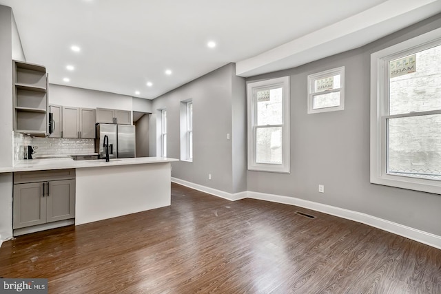 kitchen with gray cabinets, dark hardwood / wood-style flooring, sink, decorative backsplash, and appliances with stainless steel finishes