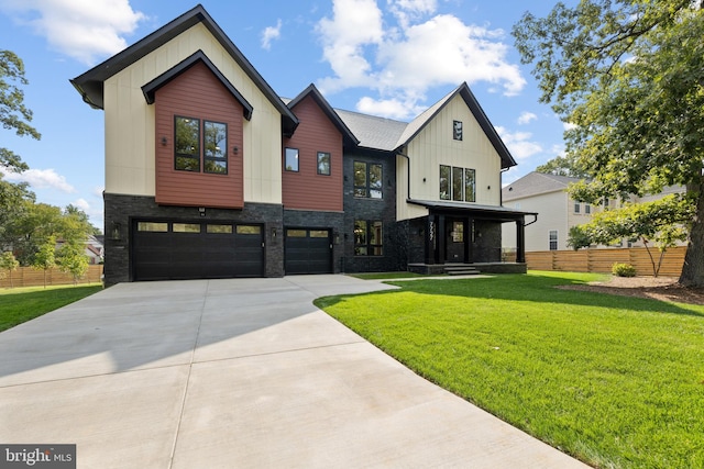 modern farmhouse featuring a garage, a front lawn, board and batten siding, and fence