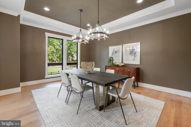 dining area with a raised ceiling, light wood-style flooring, and baseboards