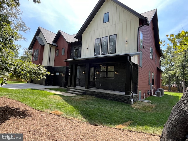 rear view of property with covered porch, central air condition unit, and a yard