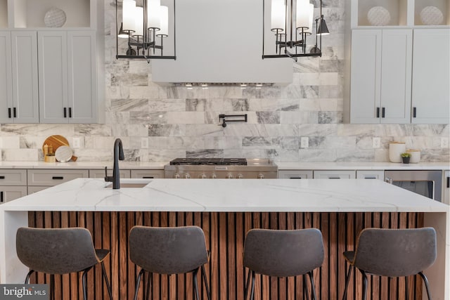 kitchen featuring light stone countertops, a breakfast bar area, pendant lighting, and sink