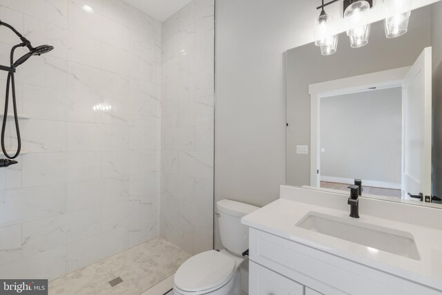 bathroom featuring tiled shower, vanity, and toilet