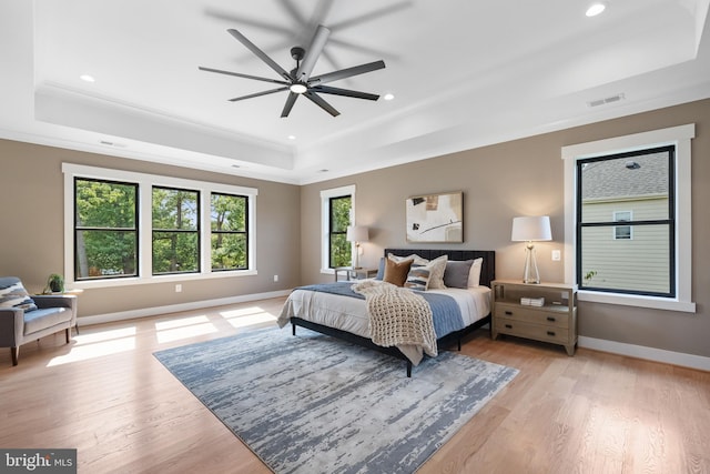 bedroom featuring ornamental molding, light hardwood / wood-style floors, a tray ceiling, and ceiling fan