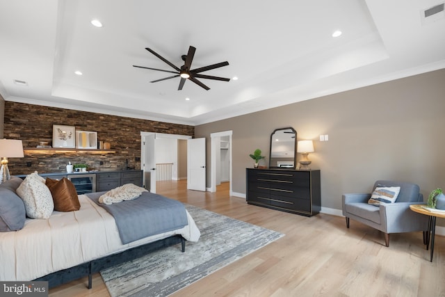 bedroom featuring ornamental molding, light hardwood / wood-style floors, a tray ceiling, and ceiling fan