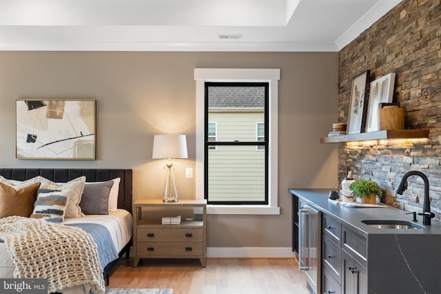 bedroom featuring beverage cooler, light hardwood / wood-style floors, crown molding, and sink