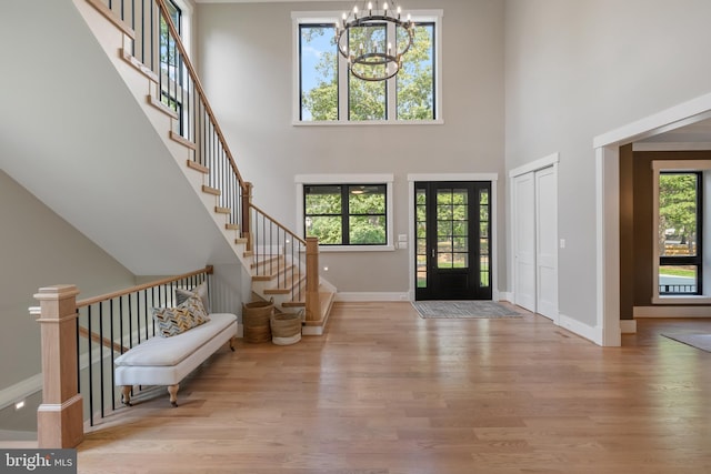 foyer entrance with a healthy amount of sunlight, light wood finished floors, and an inviting chandelier