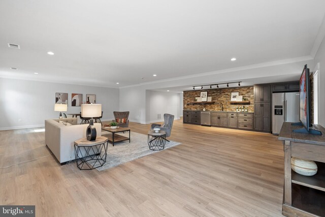 living room featuring ornamental molding, light hardwood / wood-style floors, track lighting, and sink