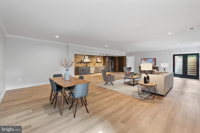 dining area with light hardwood / wood-style flooring and crown molding