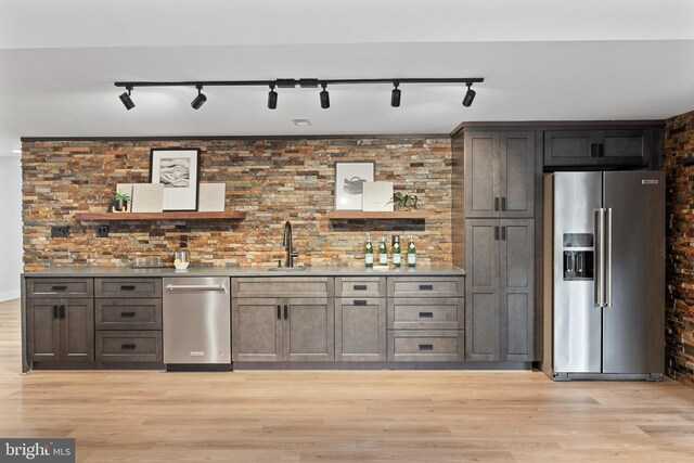 bar with appliances with stainless steel finishes, light wood-type flooring, sink, and track lighting