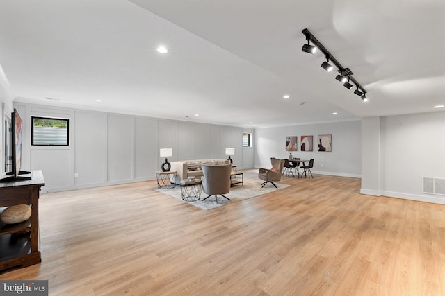 living room with light wood-type flooring and rail lighting