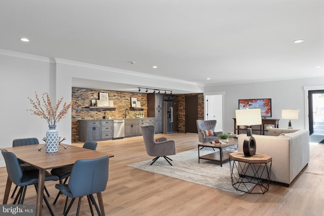 interior space featuring light wood-type flooring, ornamental molding, and track lighting