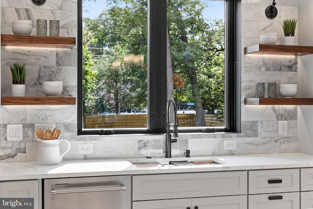 kitchen featuring light stone countertops, dishwasher, a sink, and open shelves